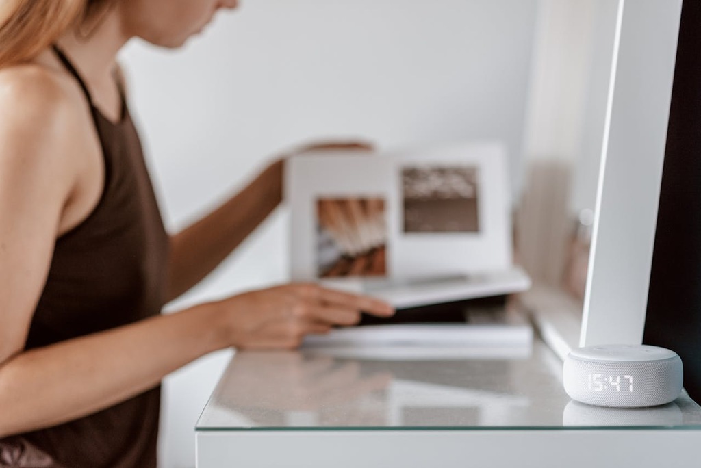 mulher lendo livro ao lado da Alexa, um dos tipos de automação residencial